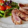 Close-up of grilled steak slices with asparagus and cherry tomatoes, perfect for a healthy meal.