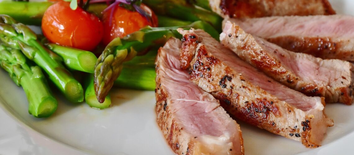 Close-up of grilled steak slices with asparagus and cherry tomatoes, perfect for a healthy meal.