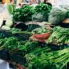 Vibrant display of fresh green vegetables at an outdoor market stall. Ideal for healthy lifestyle themes.