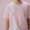 Close-up view of a person in a pink t-shirt promoting breast cancer awareness.
