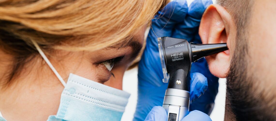 Close-up of a doctor performing an ear examination with an otoscope.