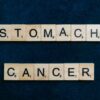Scrabble tiles spelling 'Stomach Cancer' on a dark blue background, symbolizing awareness.