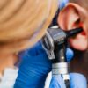 A medical professional examines a patient's ear using a Heine otoscope, highlighting healthcare quality.