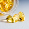 High-quality close-up of transparent softgel capsules spilled from a glass jar, showcasing vitamins or supplements.