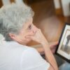 Thoughtful elderly woman with a framed photo, reflecting on memories.