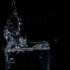Close-up of water splashing in a glass against a black background.