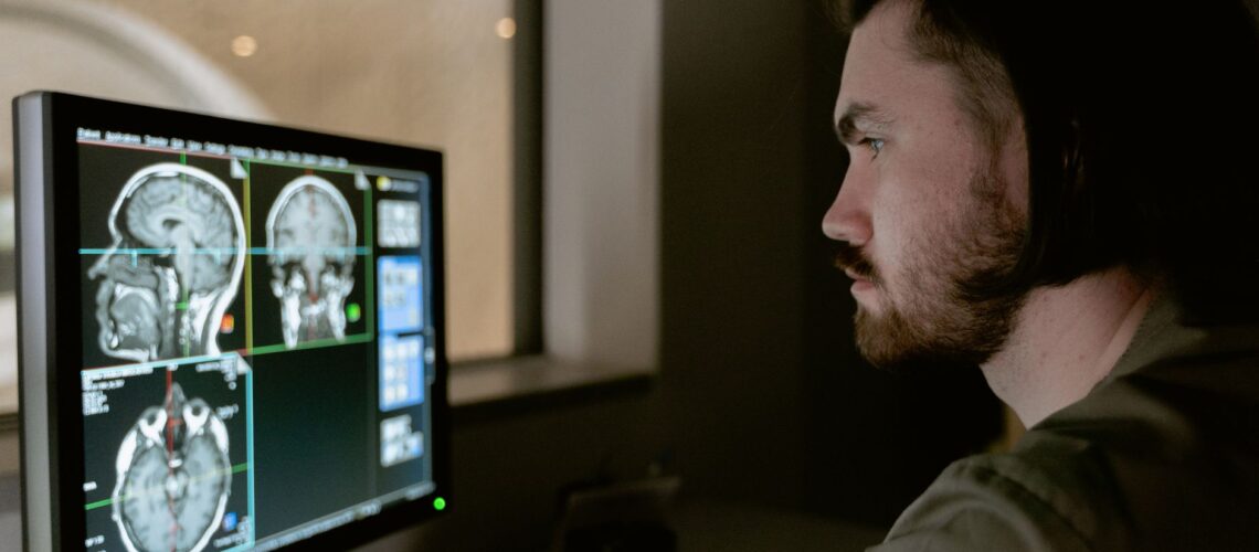 Radiologist examining a CT scan on a monitor in a medical facility.