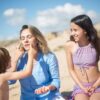 A mother with her kids applying sunscreen on a sunny beach in Portugal.