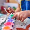 A close-up of a child finger painting with vibrant colors, showcasing creativity and focus.