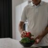 Elderly man in kitchen holding vegetables, embracing a healthy lifestyle.