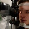 Serious female patient looking at light from contemporary ophthalmic bio microscope while getting eyesight examination in modern clinic during check up