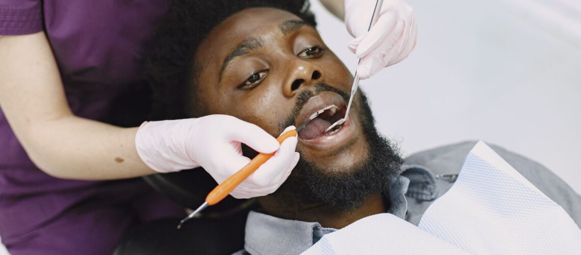 Dentist examining a man's teeth during a routine dental checkup.