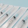Close-up of sterile syringes aligned on a light blue surface, highlighting medical equipment.