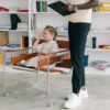 A child in a therapy session with a therapist holding a clipboard.