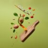 A creative arrangement of paleo diet ingredients floating above a wooden board on a green background.