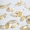 Close-up of yellow transparent softgel capsules on a white background, suitable for pharmaceutical or supplement themes.