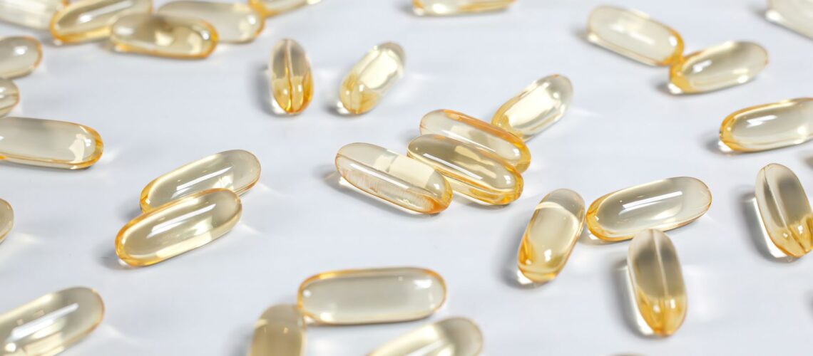 Close-up of yellow transparent softgel capsules on a white background, suitable for pharmaceutical or supplement themes.