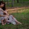 A mother lovingly breastfeeding her child in a peaceful outdoor setting.