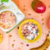 Colorful bowls of creamy muesli and fresh fruits on a wooden table, perfect for a healthy breakfast.