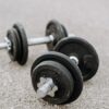 Massive metal dumbbells prepared for difficult healthy training on asphalt road in summer