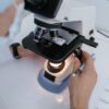 Close-up of a scientist examining samples under a microscope in a laboratory setting.