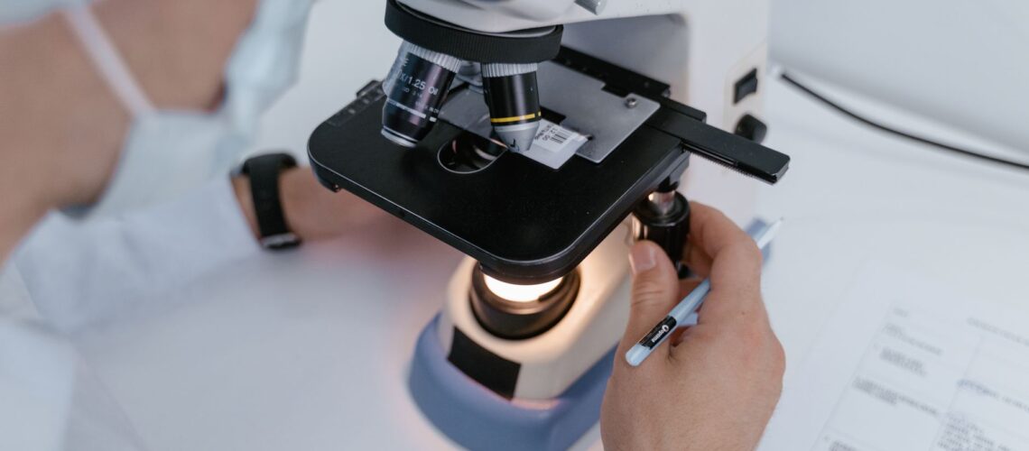Close-up of a scientist examining samples under a microscope in a laboratory setting.