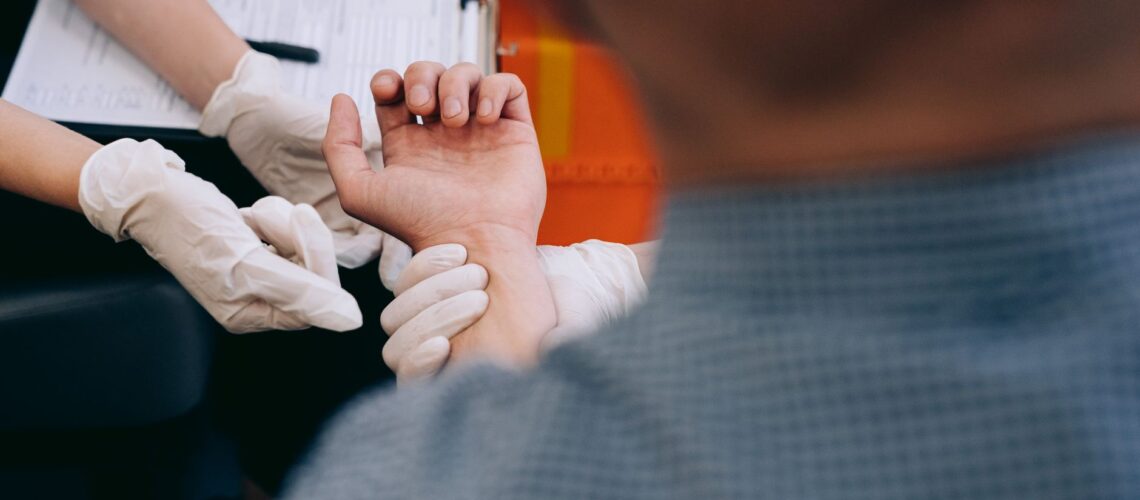 Healthcare professional checks man's pulse during medical examination.