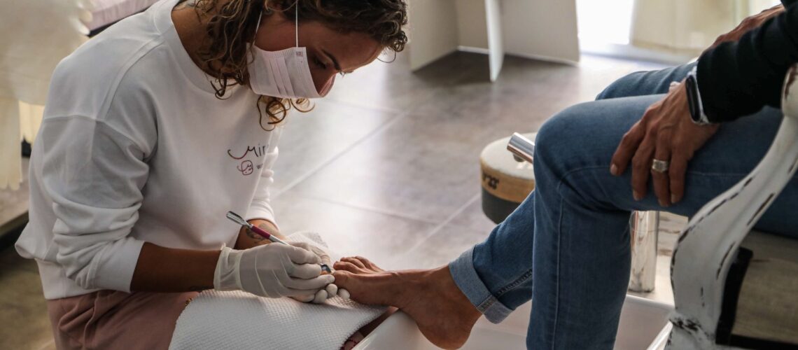 A beauty technician performs a pedicure, providing professional foot care at a salon.