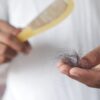 A detailed image showing hair loss with a comb in hand, symbolizing alopecia and related issues.