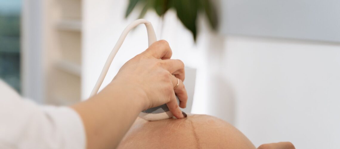 A close-up of a healthcare professional conducting an ultrasound on a pregnant woman.