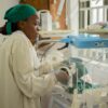 A nurse tends to a newborn in an incubator, ensuring health and safety in a hospital setting.