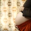 Intimate close-up of a pregnant woman's belly with hands touching, showcasing motherhood and love.