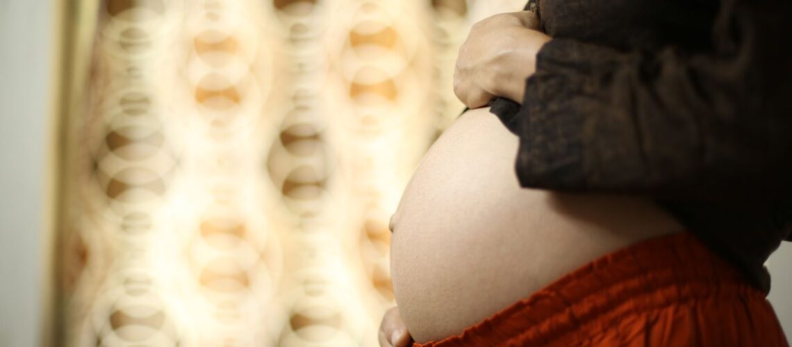 Intimate close-up of a pregnant woman's belly with hands touching, showcasing motherhood and love.