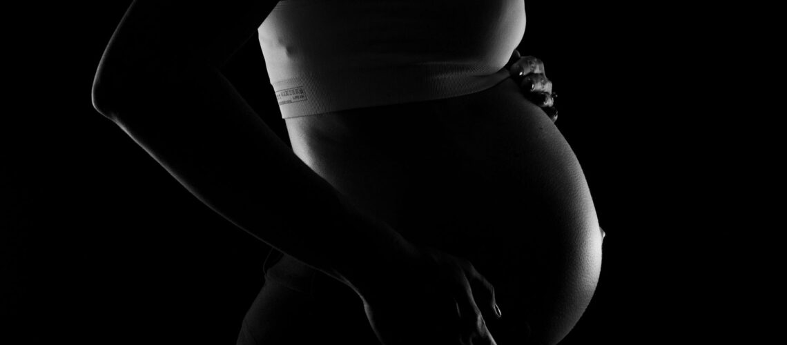Captivating grayscale close-up of a pregnant woman highlighting a baby bump, conveying anticipation and love.