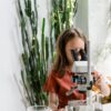 A curious child examines samples through a microscope in a plant-filled space, fostering learning and discovery.