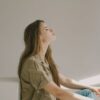 Side profile of a young woman sitting indoors, lost in thought with eyes closed.