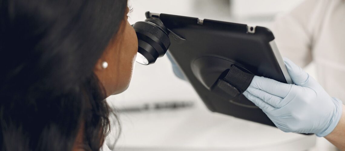 Dermatologist examining a patient's skin using a digital dermatoscope and tablet for precision observation.