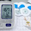 A close-up shot of medical equipment including blood pressure monitor and pills on an ECG graph.