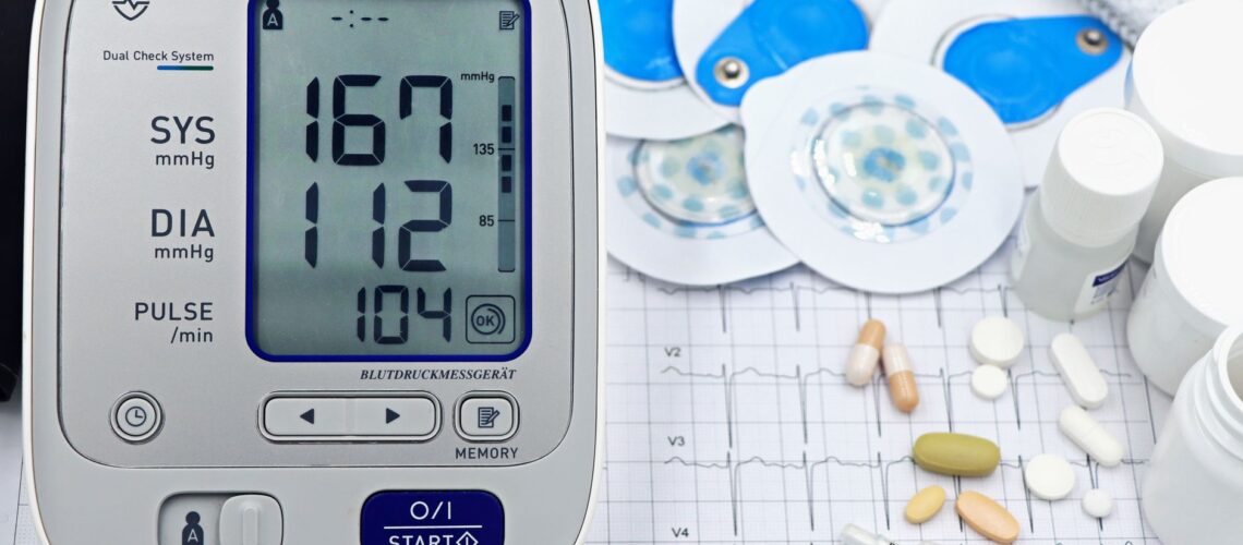 A close-up shot of medical equipment including blood pressure monitor and pills on an ECG graph.