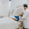 Doctor assisting patient in MRI scanner during medical examination in hospital setting.