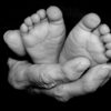 A touching black and white close-up of a baby's feet cradled in elderly hands, symbolizing care and connection.