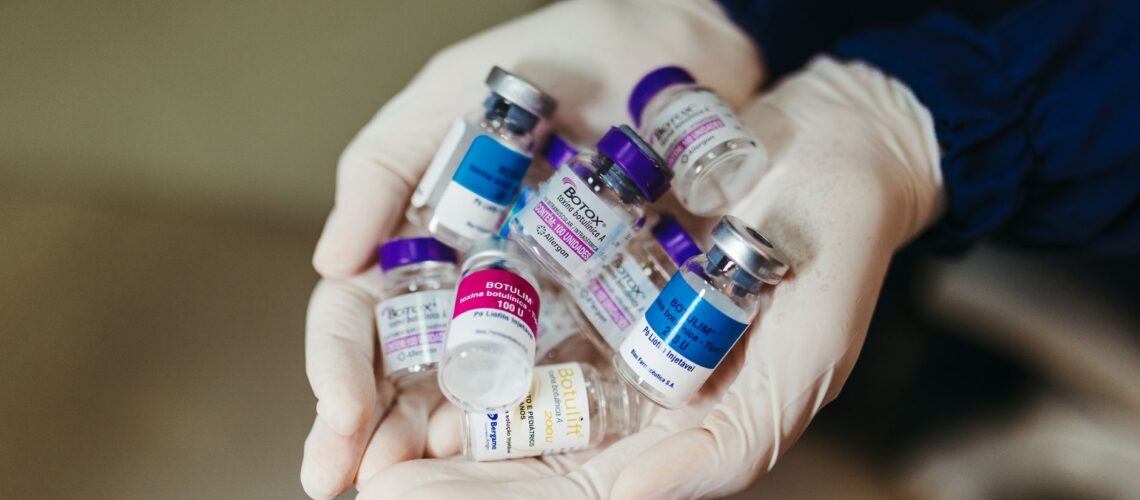 Close-up of gloved hands holding botulinum toxin vials in a laboratory, ideal for medical themes.