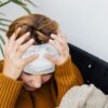 Woman with head injury holding her head in pain indoors.