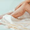 A close-up view of a woman's legs with varicose veins wrapped in a luxurious satin blanket. Health and skincare concept.