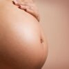 An intimate close-up of a pregnant woman's abdomen, highlighting maternity and parenthood.