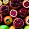 A colorful assortment of fresh fruits including pomegranates, lemons, and grapefruits.