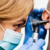Gros plan d'un médecin effectuant un examen de l'oreille avec un otoscope.