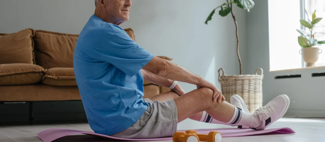 Un homme âgé fait de l'exercice à domicile avec du yoga et des poids pour un mode de vie sain.