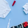 Vue à plat d'accessoires de bébé et d'un test de grossesse sur fond bleu.