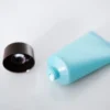 Vue de dessus d'un tube ouvert de crème nourrissante brillant avec son couvercle sur fond clair.